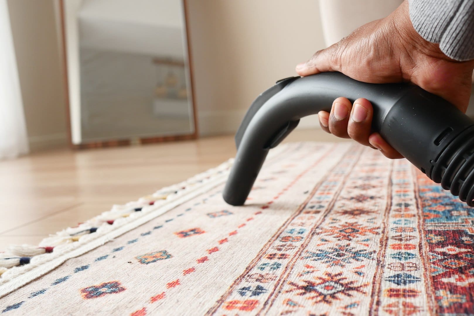 Close-up of gentle suction-only vacuuming on a fine area rug - safe at-home silk rug maintenance between professional cleanings