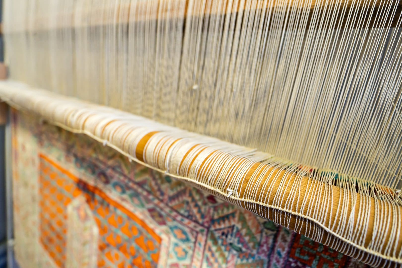 Traditional handwoven silk rug on a loom showing the delicate fibers that require professional silk rug cleaning care