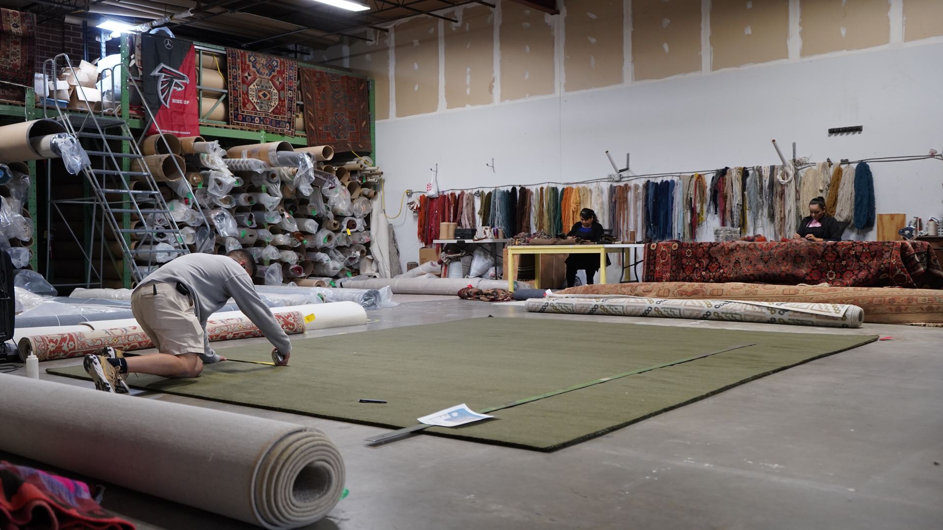 Rug repair workshop at S&S Rug Cleaners in Atlanta with a wall of color-matched yarn used for fringe and edge repairs