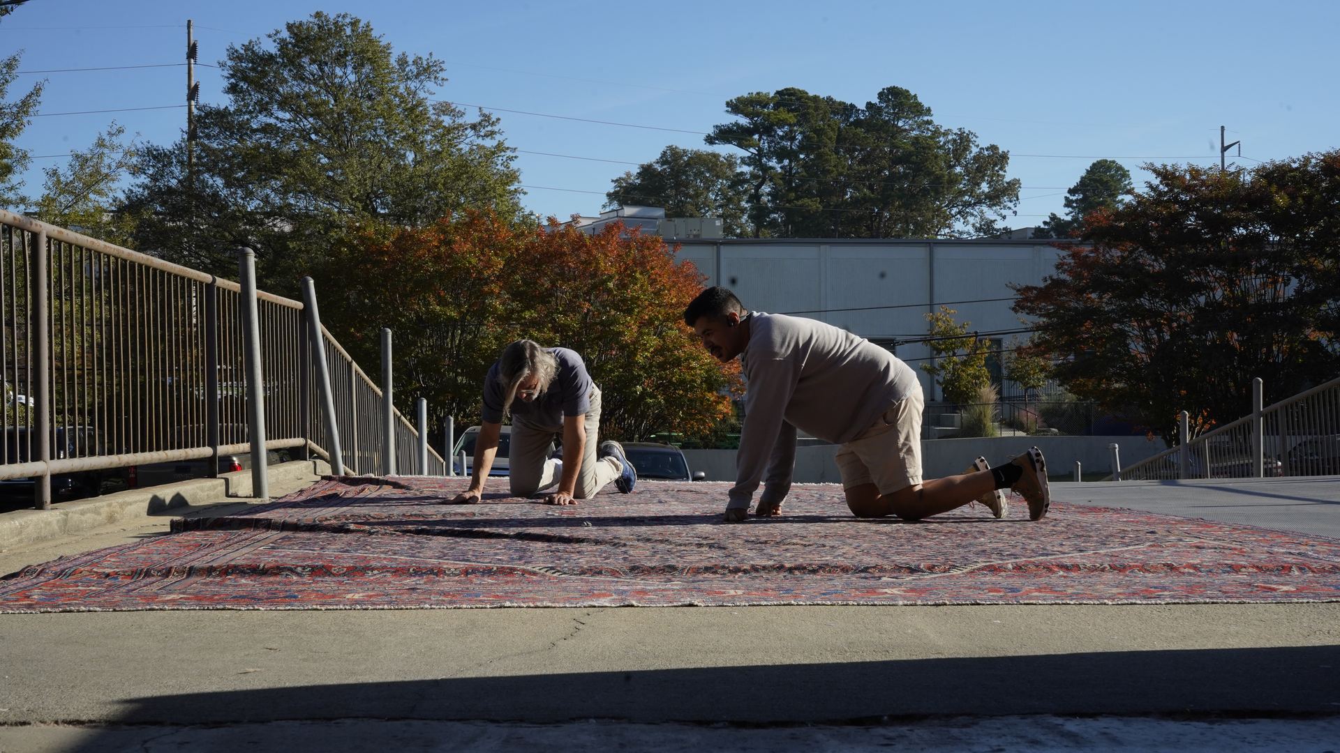 S&S Rug Cleaners technicians inspecting the edges and fringe of a large Oriental rug laid out in the sun in Atlanta