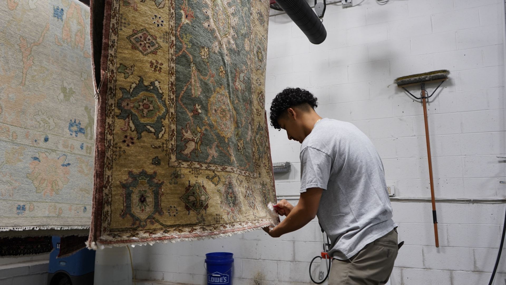 Technician inspecting a hanging area rug for dye stability and fiber condition at S&S Rug Cleaners in Atlanta before cleaning