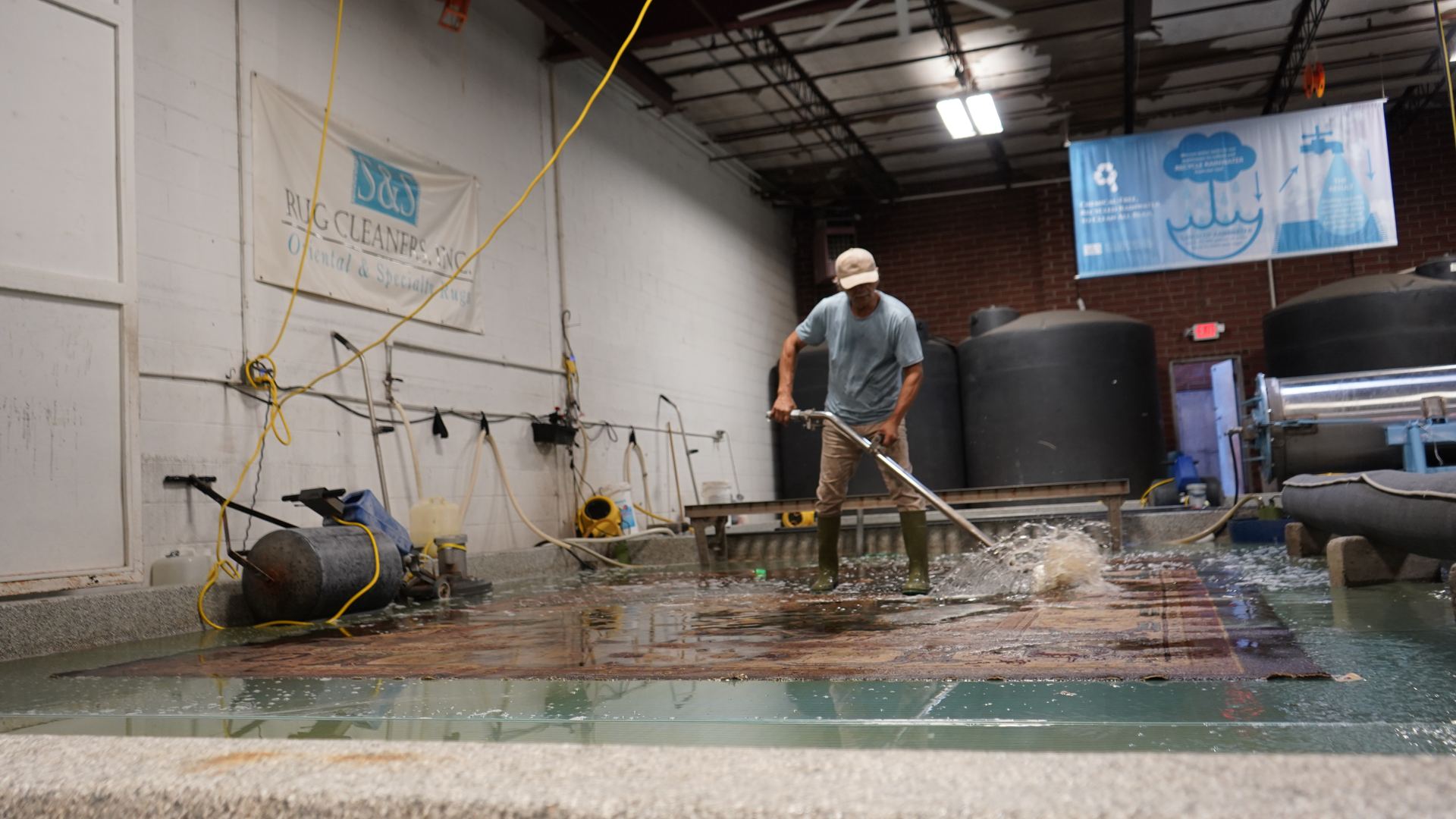 S&S Rug Cleaners technician flushing a red hand-knotted rug with cool water on the wash floor to rinse loose dye in Atlanta