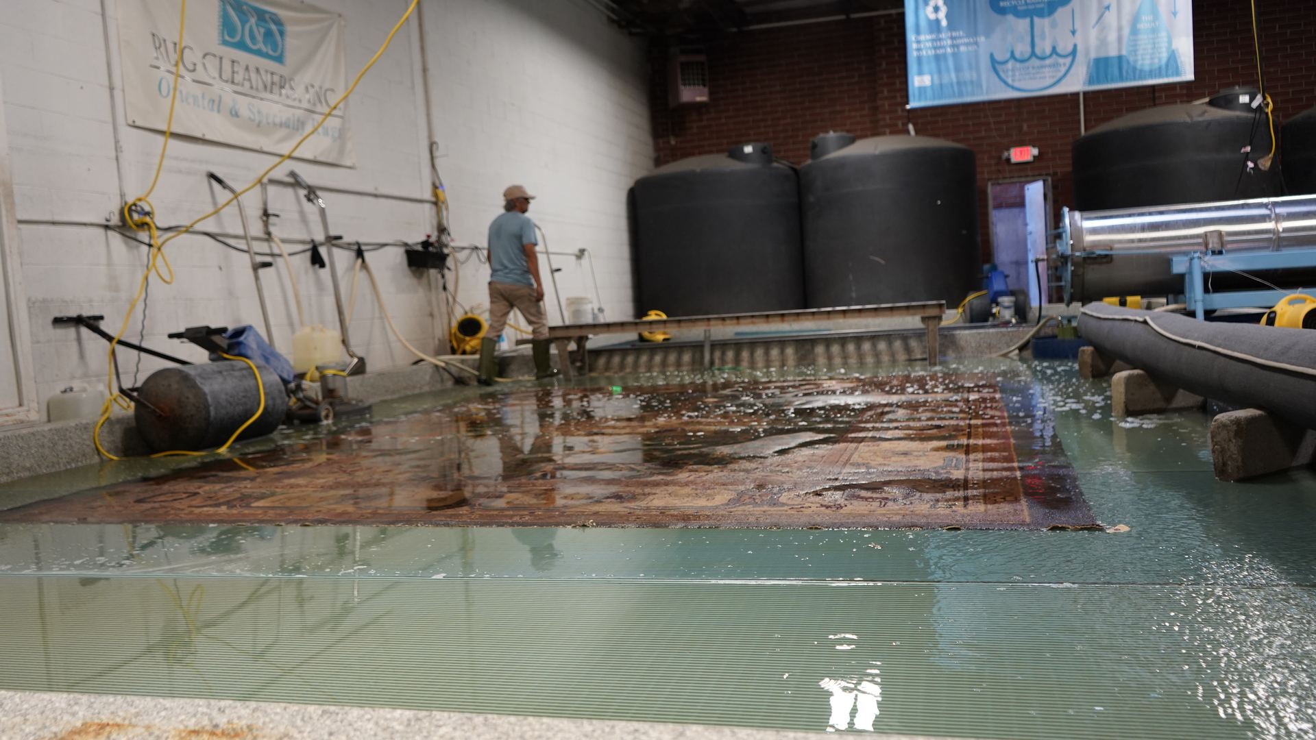 Hand-knotted Oriental rug submerged in the S&S Rug Cleaners wash pit during a full immersion wash in Atlanta