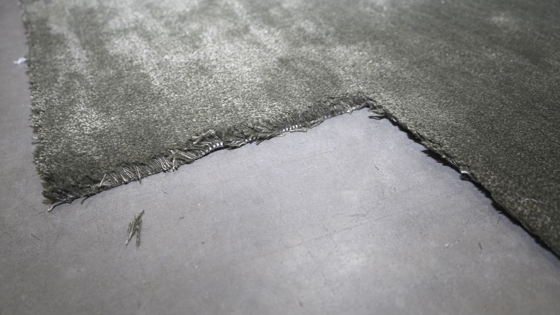 Close-up of a plush high-pile area rug laid flat on the floor at S&S Rug Cleaners, showing the deep, soft fibers that make shag rugs hard to clean